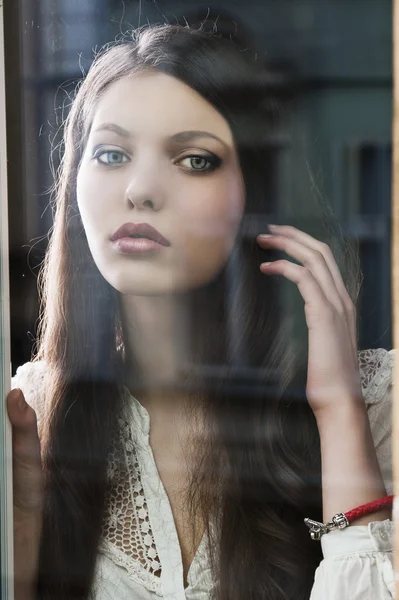 Myšlení žena u okna wuth ruku poblíž vlasy — Stock fotografie