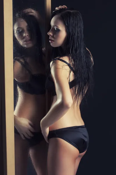 Sexy Frau in Unterwäsche steht neben einem Spiegel — Stockfoto