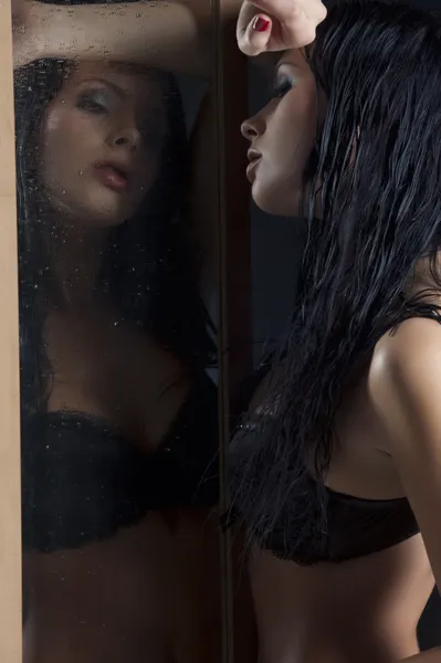 Femme sexy en sous-vêtements noirs à côté d'un miroir — Photo