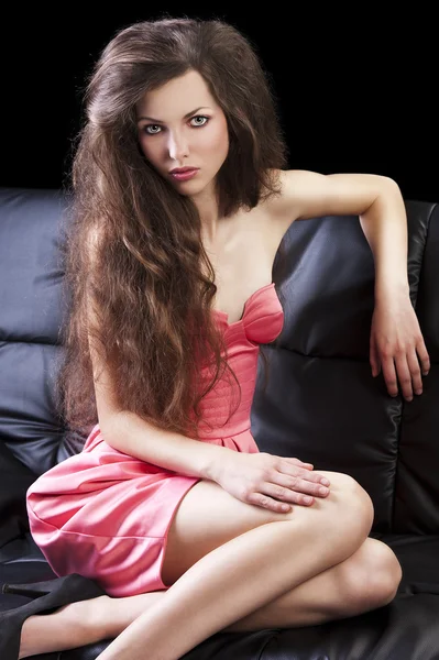 Brunett i rosa soffan, hon har armbågen på rygg i soffan — Stockfoto