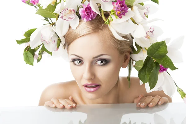Bonita rubia con corona de flores en la cabeza, mira a la izquierda con una — Foto de Stock