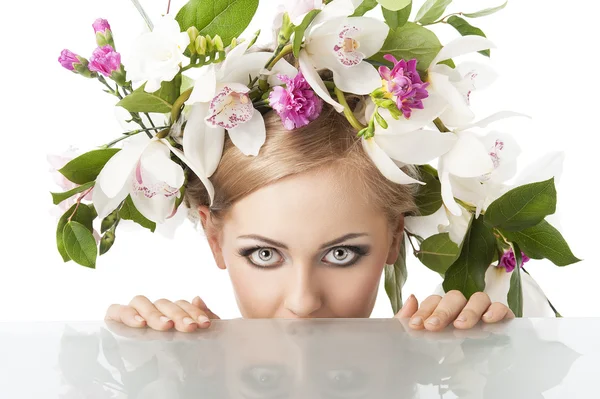 Hübsche Blondine mit Blumenkrone auf dem Kopf, sie sitzt hinter dem Tisch — Stockfoto