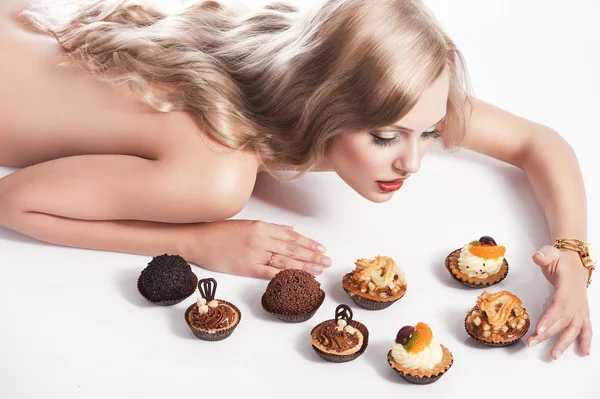 Ξανθιά σέξι κορίτσι τρώει ζαχαροπλαστικής, μοιάζει αρτοσκευάσματα — Φωτογραφία Αρχείου
