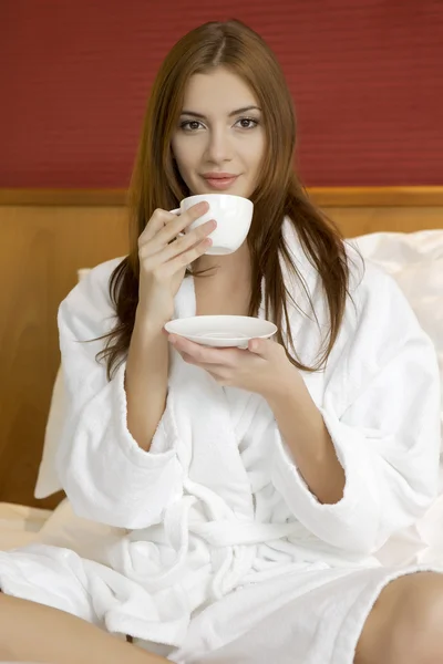 Porträt einer schönen Frau mit Tasse auf dem Bett — Stockfoto