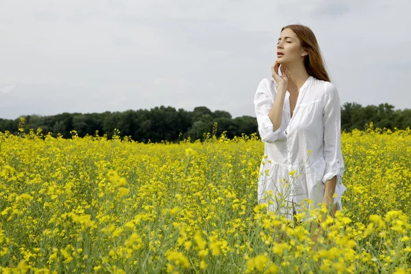 Brunette vrouw in een gele bloemen veld — Stockfoto