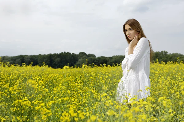 Bruneta žena v poli žluté květy Royalty Free Stock Fotografie