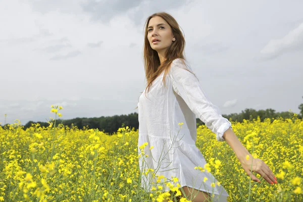 黄色の花のフィールドにブルネットの女性 — ストック写真