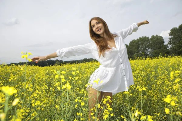 Brunette femme dans un champ de fleurs jaunes — Photo