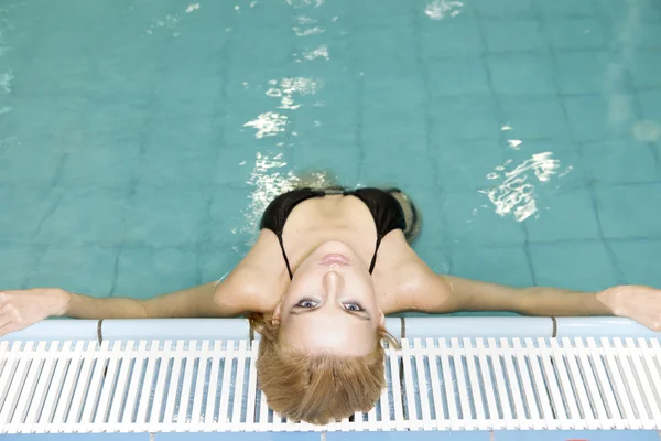 Schöne junge Frau steht in einem Swimmingpool — Stockfoto