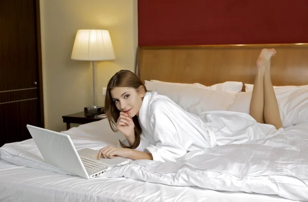 젊은 여자는 노트북으로 흰색 소파에 누워. — 스톡 사진