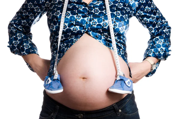 Ventre de femme enceinte avec de petites chaussures — Photo