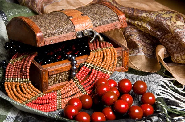 Old jewelery chest with necklaces placed on scarves — Stock Photo, Image