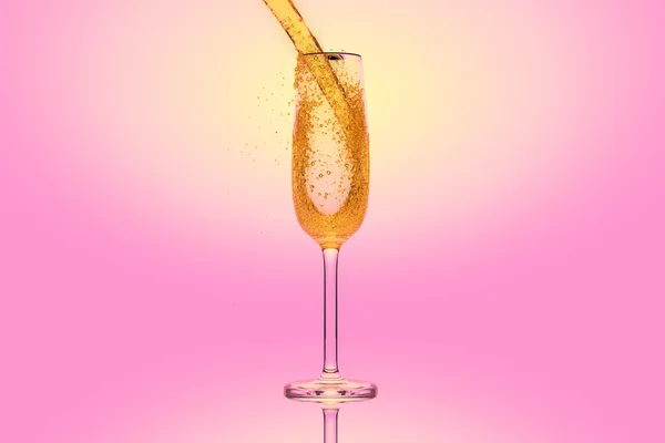 Champagne in un bicchiere su sfondo rosa — Foto Stock