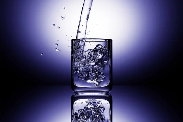 stock image Glass of water splashing on the dark background