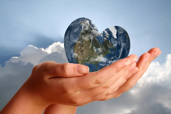 Heart shaped world in young womans hands — Stock Photo, Image