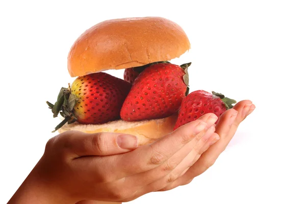 Två unga händer erbjuder jordgubbar på en bulle — Stockfoto