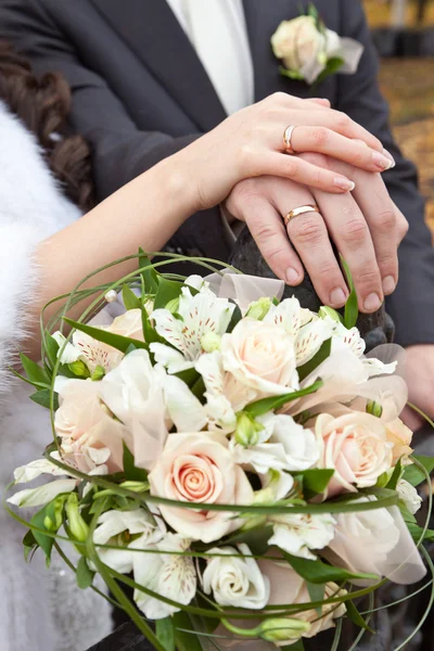 Свадебный букет и руки с обручальными кольцами — стоковое фото