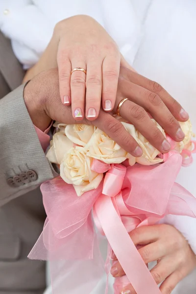 Las manos del novio y la novia con anillos de boda en un ramo de bodas — Foto de Stock