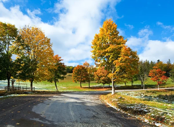 Primeiro inverno neve e outono folhagem colorida perto da estrada da montanha — Fotografia de Stock