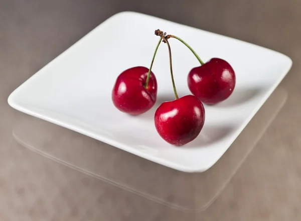 Three cherries on a plate — Stock Photo, Image