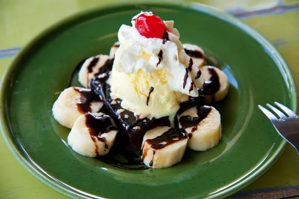 Una cucharada de helado de vainilla cubierta con plátano, crema, jalea roja y ch —  Fotos de Stock