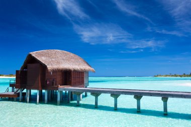 Overwater villas in blue lagoon of an island clipart