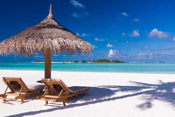 Sillas y sombrilla en una playa con sombra de palmera — Foto de Stock