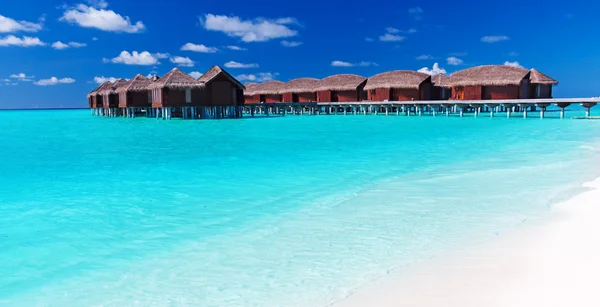 Overwater villas in blue tropical lagoon with white beach — Stock Photo, Image