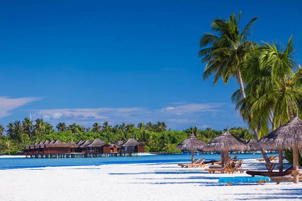 Palmeras sobre la playa tropical de arena con villas sobre el agua — Foto de Stock