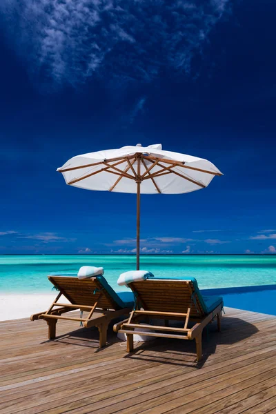 Chaises longues et piscine à débordement au-dessus du lagon tropical — Photo