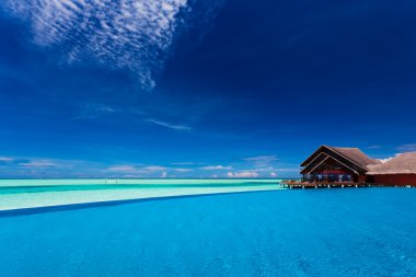 Infinity pool over tropical lagoon with clear blue sky clipart