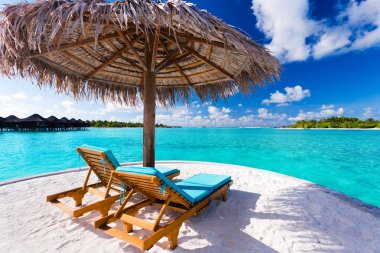 Two chairs and umbrella on tropical beach clipart