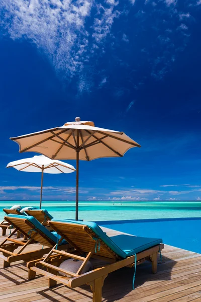 Tumbonas y piscina infinita sobre laguna tropical — Foto de Stock