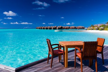 Table and chairs at beach restaurant clipart