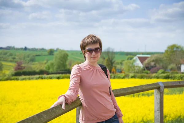 Young woman on a backgroun dof rapeseed field — Stock Photo, Image