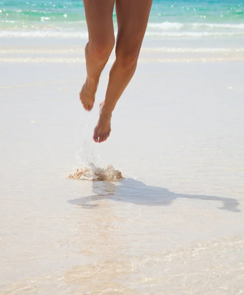 Weibliche Beine im flachen Wasser — Stockfoto