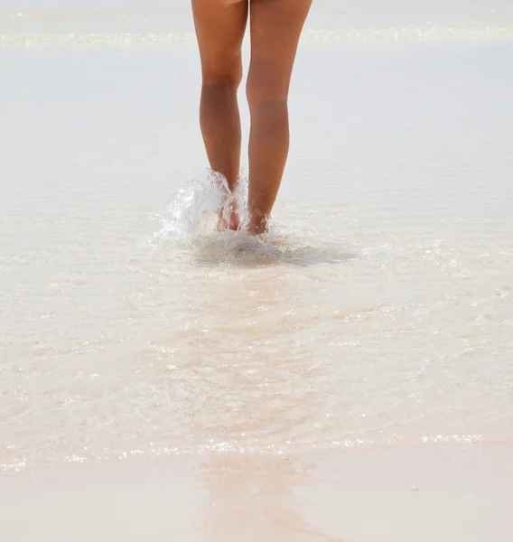 Weibliche Beine im flachen Wasser — Stockfoto