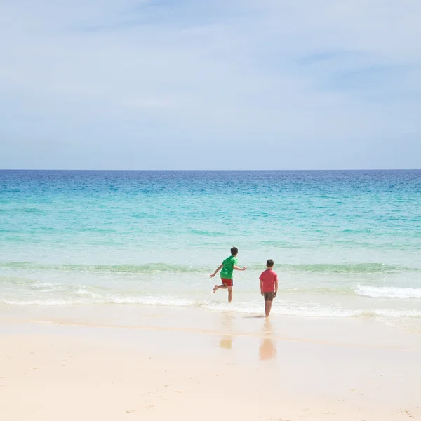 Σε μια παραλία - δύο αγόρια με κόκκινα και πράσινα μπλουζάκια και τα σορτς για να — Φωτογραφία Αρχείου