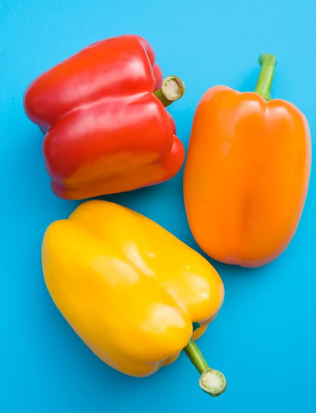 Laranja; pimentas doces vermelhas e amarelas em placa de corte de plástico azul brilhante — Fotografia de Stock