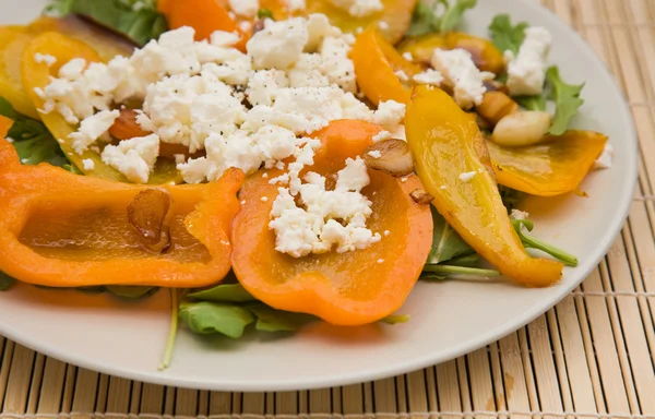 Summer light meal -- fried sweet pepper with garlic and crumbled feta cheese, on a bed of rocked salad — Stock Photo, Image