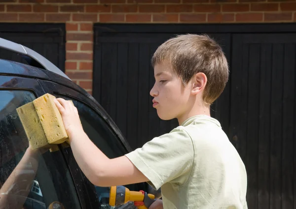 stock image Cute little serious boy washing black car outside in siunshine