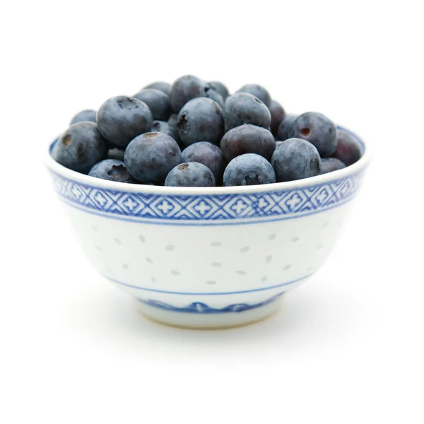 Färska mogna blåbär i en liten blå skål, isolerad på vit bakgrund — Stockfoto