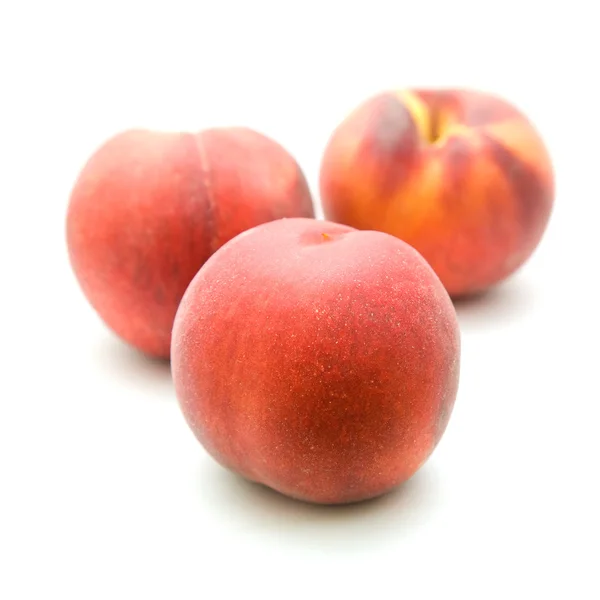 Três pêssegos vermelhos maduros isolados sobre fundo branco — Fotografia de Stock