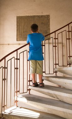 kleine jongen in blauwe shurt fotograferen iets permanent op spiraal stircase met zijn rug naar de standpunten