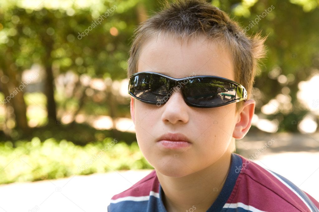 Little caucasian boy in dark shades in sunny park