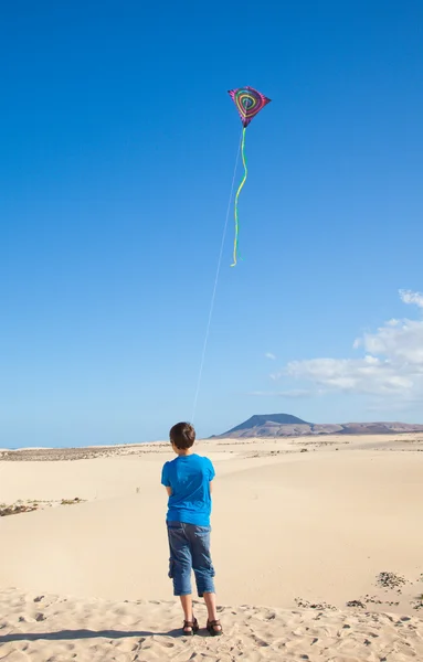 Liten pojke flyger en drake i sanddynerna i corralejo, fuerteventura — Stockfoto