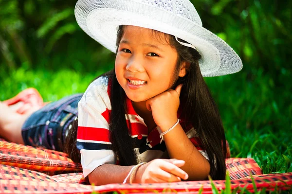 stock image Young girl lying on a meadow with a hat on her head