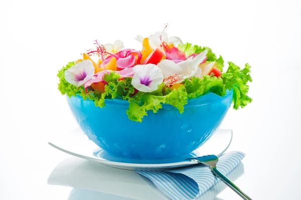 Фруктовый салат с съедобными цветами в голубой миске из льда на белом — стоковое фото