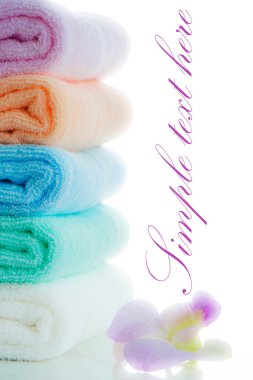 Multicolor towels stacked with a orchid flower on white backgrou clipart