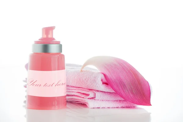 Una toalla rosa con un pétalo de loto y una botella de cosmética en whi —  Fotos de Stock